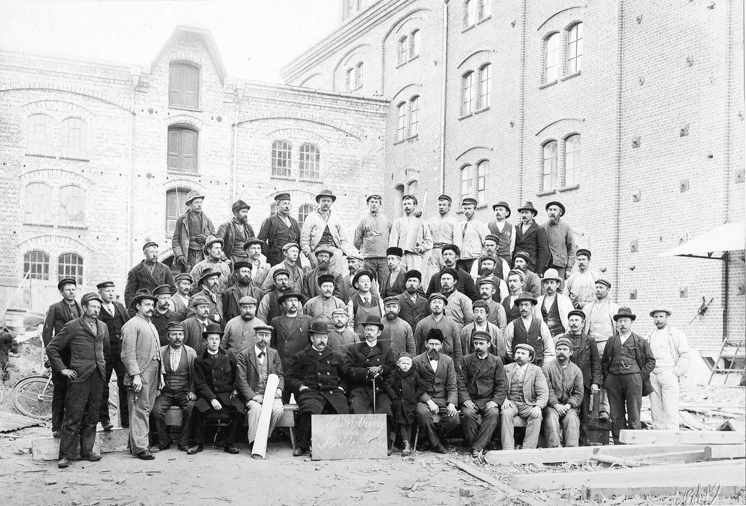 "Erindring fra monteringen 1901". Arbeidere oppstilt foran det som i dag er hovedinngangen til GRAC. Samme inngang, ny tid.